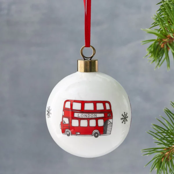 Porcelánová vánoční ozdoba s obrázkem červeného autobusu.